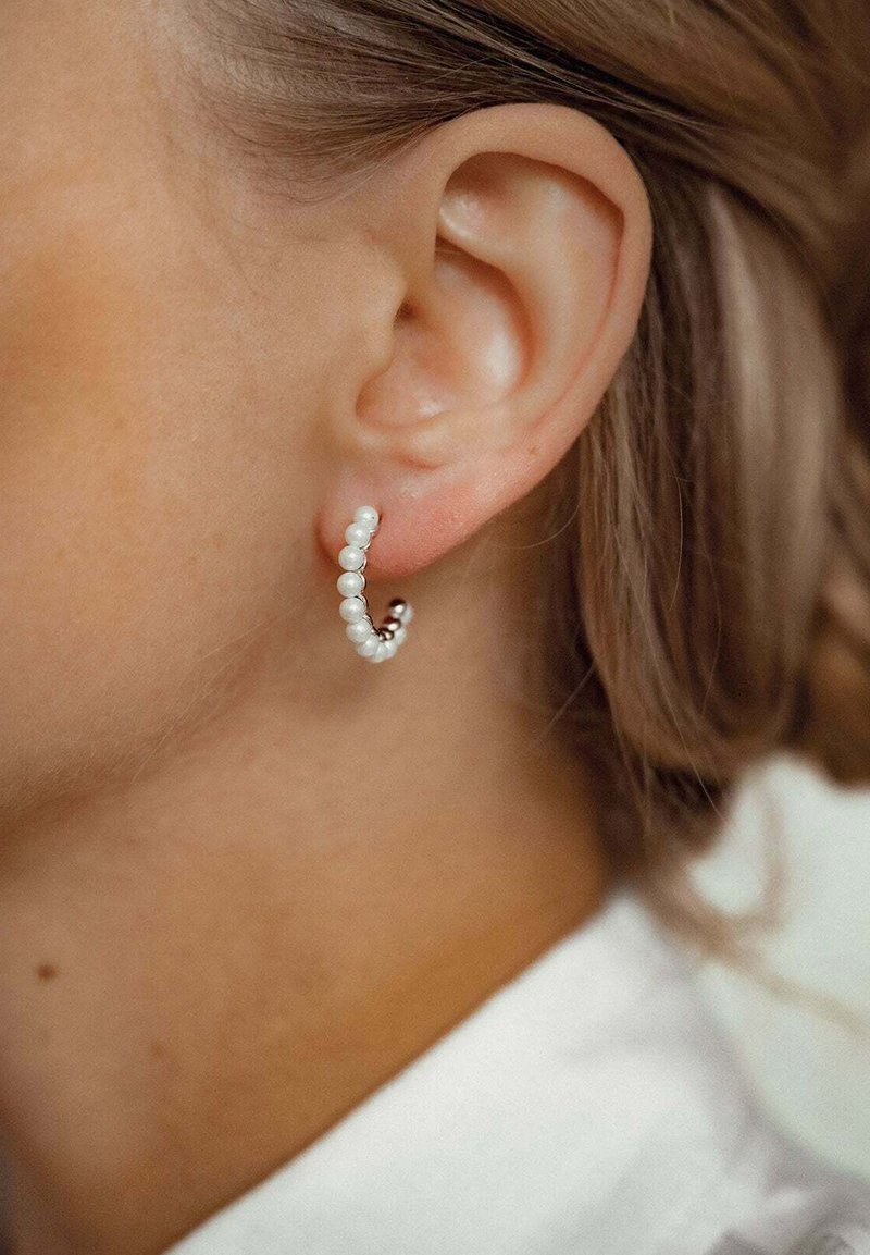 Boucles d'oreilles en forme de créoles, ornées de petites perles blanches alternées avec des accents en argent, avec un design courbé qui épouse étroitement le lobe de l'oreille.
