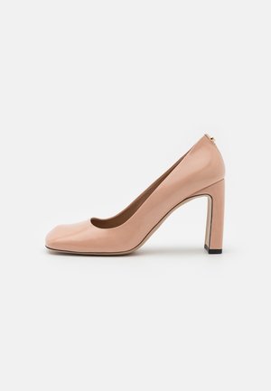 Escarpin à talon haut en cuir verni nude avec un bout arrondi, un design élégant et un talon carré ; présente un subtil accent doré à l'arrière.