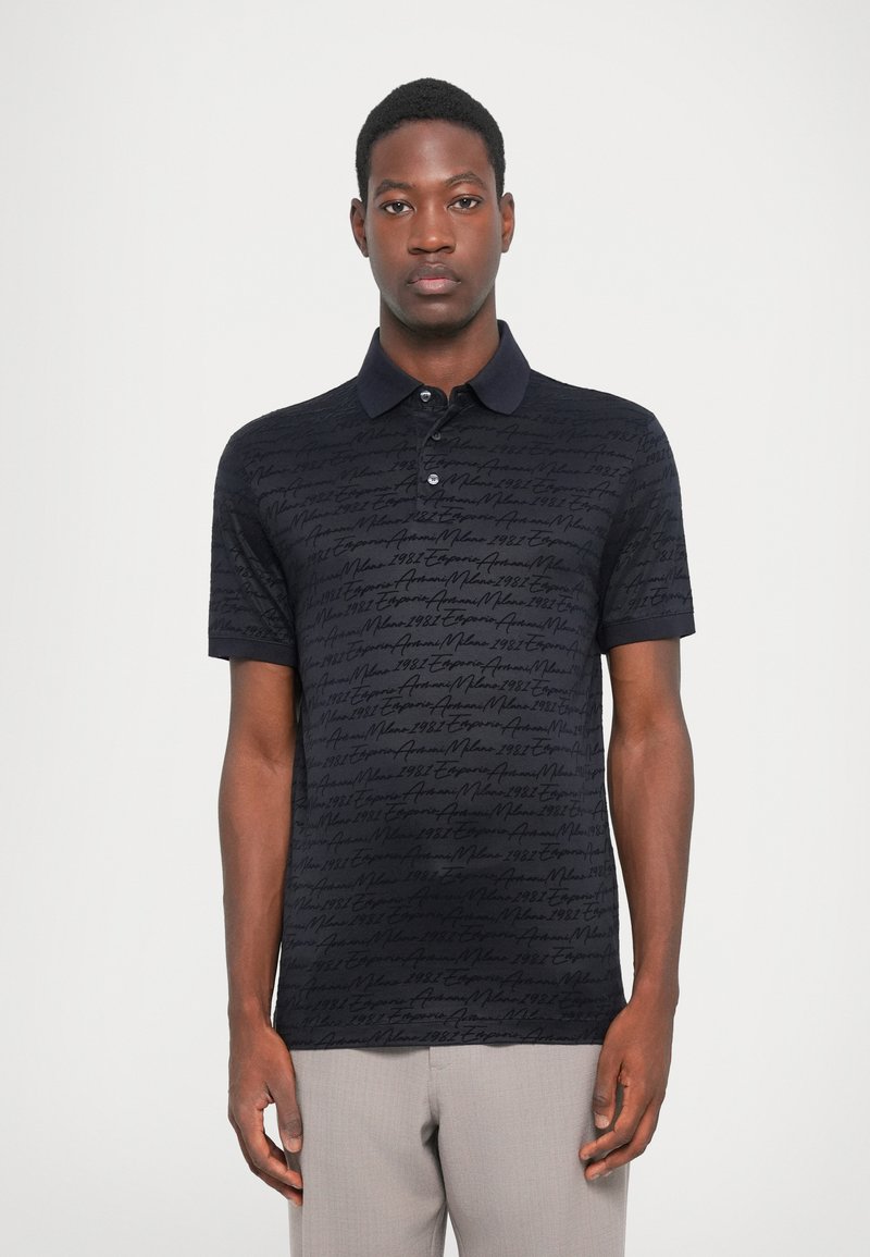 Svart polo skjorte med et teksturert mønster av kursiv tekst. Knapp krage, korte ermer og en slim fit-design.