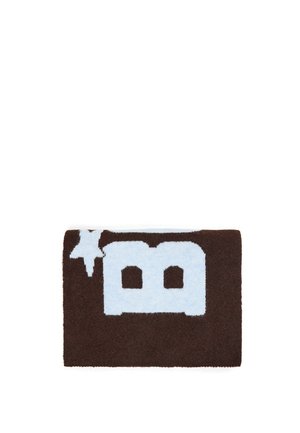 Pièce tricotée rectangulaire marron avec une grande lettre majuscule bleue claire "B" et une forme d’étoile dans le coin supérieur gauche.