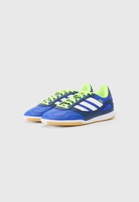 Zapatillas deportivas azules y marinas con cordones verdes, rayas blancas y suela de goma; parte superior sintética lisa con paneles texturizados.