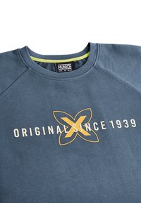 Sudadera azul de algodón, con cuello redondo, mangas raglán y texto en negrita "ORIGINAL SINCE 1939" en blanco y amarillo.