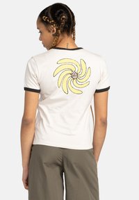 Witte katoenen t-shirt met korte mouwen, zwarte rand, met een afbeelding van een draaiende gele bananen op de achterkant. Gladde textuur.