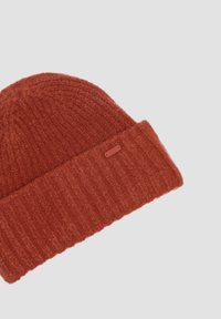 Beanie lavorato a maglia di colore ruggine, realizzato in tessuto morbido, dotato di una texture a coste e di una cuffia piegata con una piccola etichetta di marca.