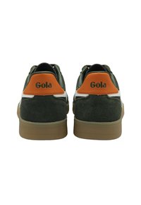 Gröna mockaskor med vita accenter, orange hälflik med "Gola"-logotyp och sula i naturgummi; klassisk lågtoppdesign.