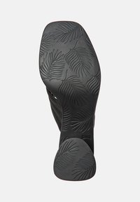 Semelle de chaussure noire avec un motif en forme de feuille, fabriquée en caoutchouc, avec un bord arrondi et une finition lisse. Taille marquée comme 38.