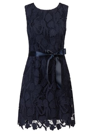 Marineblauwe kant jurk met mouwloos ontwerp, bloemenpatroon, gegolfde zoom en een satijnen riemstrik rond de taille.