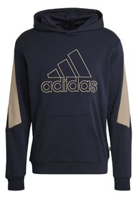 Hoodie bleu marine avec des accents crème sur les manches, arborant un grand logo beige d'Adidas sur le devant et une poche kangourou à l'avant.