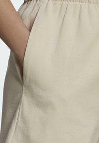Beiga bomullssweatpants med elastisk midja och sidfickor, som har en mjuk struktur och en avslappnad design.