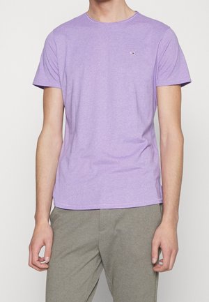 T-shirt lilas à manches courtes en tissu doux et texturé. Il présente un col rond et un petit accent logo sur le côté gauche de la poitrine.