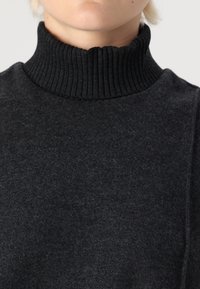 Pullover grigio scuro con colletto a dolcevita a coste. Realizzato in tessuto morbido, presenta una finitura testurizzata e un design pulito e minimalista.