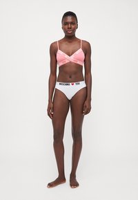 Bralet roz cu bretele încrucișate și text alb; asortat cu chiloți albi cu branding negru "MOSCHINO ♥ YOU" în jurul taliei.