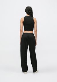 Čierny krátky tielkový top a čierne široké nohavice. Hladká tkanina, elastický pás a minimalistický dizajn bez viditeľných vzorov.