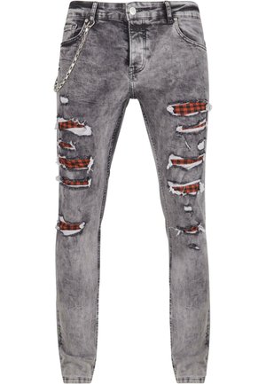 Grå, slitte jeans med flere hull som avslører rødt og svart rutete stoff under. Har detaljer med kjede på siden og en smal passform.