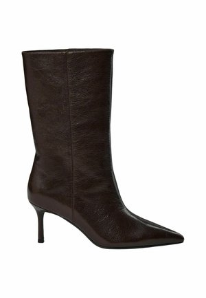 Bottes en cuir marron foncé jusqu'au milieu du mollet avec un bout pointu et un talon fin et haut sur fond blanc.