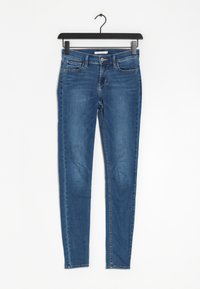 Jean en denim bleu slim avec une taille mi-haute, des poches avant et une texture lisse. Présente une légère décoloration et un design classique à cinq poches.