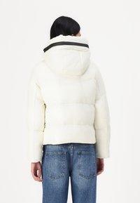 Padded white jacket with a black-accented hood, featuring a cropped design, straight sleeves, and a smooth, textured finish.