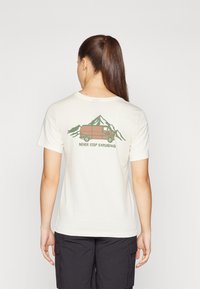 Krémové tričko s potiskem zelených hor a dodávky a textem "NEVER STOP EXPLORING". Krátké rukávy, kulatý výstřih, měkká textura.