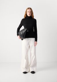 Černý dlouhý rukáv turtleneck top s přiléhavým střihem, kombinovaný s vysokým pasem širokými bílými kalhotami a černou koženou kabelem.