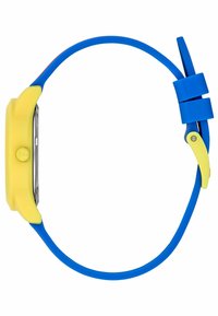 Montre colorée avec un boîtier en silicone jaune, un bracelet en silicone bleu, et un cadran argenté avec un bouton jaune et des accents métalliques.