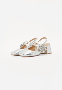 Scarpe slingback metalliche argento con tacco basso a blocco, dotate di tre cinturini decorativi e di un accento di strass sul tacco.