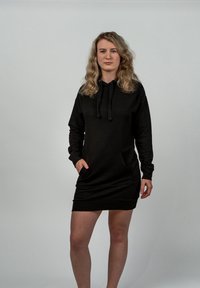 Černé mikinové šaty s kapucí, přední kapsou, dlouhými rukávy a stahovací šňůrkou. Měkká tkanina s uvolněným střihem, dosahující do poloviny stehen.