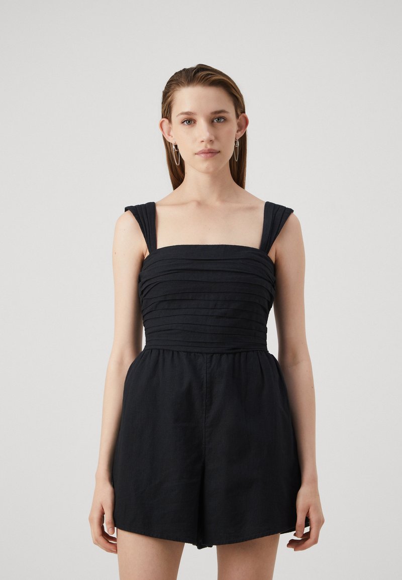 Mono negro con escote cuadrado, tirantes anchos y textura fruncida en el busto. Tejido suave con un ajuste relajado.