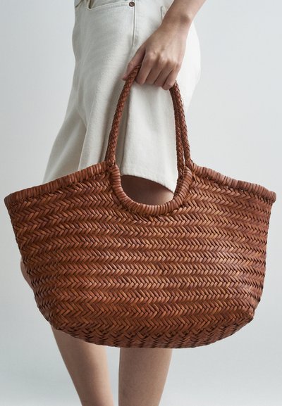 Καφέ πλεκτή δερμάτινη τσάντα tote με στρογγυλή κορυφή και διπλές λαβές, που προβάλλει ένα υφασμάτινο μοτίβο και σημαντικό μέγεθος για τη μεταφορά αντικειμένων.