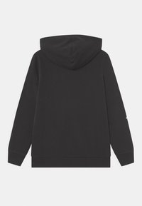 Felpa nera con una texture morbida, dotata di tasca a marsupio, polsini a coste e cappuccio regolabile con lacci. Design minimalista senza loghi visibili.