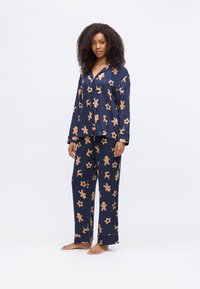 Navy pyjama set met lange mouwen en broek, versierd met patronen van peperkoekmannetjes en sterren in lichtbruin, gemaakt van zachte stof.