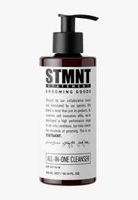 Mörkbrun flaska med en svart pumpkork. Etiketten har fet svart text på en vit bakgrund som beskriver "All-in-One Cleanser" och varumärket.