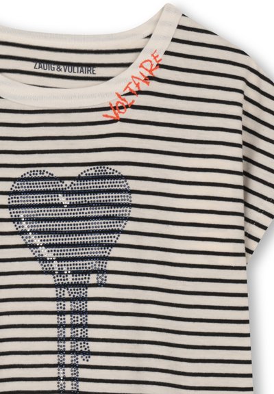 T-shirt en coton rayé crème et noir avec un motif cœur en sequins bleus et le texte brodé en rouge "VOLTAIRE" près de l'encolure.