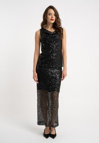 Czarna sukienka z cekinami, bez rękawów, z dekoltem typu kapturek i przezroczystą dolną częścią. Charakteryzuje się dopasowanym krojem i długością do podłogi.