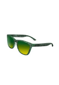 Gafas de sol verdes con un patrón, con un marco texturizado, lentes en degradé de verde a amarillo, y un diseño moderno y anguloso.
