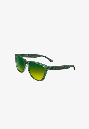 Gafas de sol verdes con un patrón, con un marco texturizado, lentes en degradé de verde a amarillo, y un diseño moderno y anguloso.