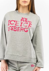 Grauer Sweatshirt mit großem rosa "ICEBERG"-Text, Rundhalsausschnitt und langen Ärmeln. Weicher Stoff mit lässiger Passform und gerippten Bündchen.