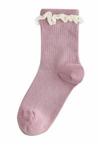 Różowa prążkowana skarpetka z białą, falbankową koronkową lamówką u góry. Posiada wzmocnione palce i piętę, wykonana z miękkiego, elastycznego materiału.