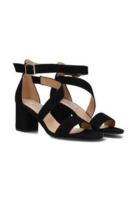 Zwarte suedine hoge sandalen met enkelbandje, kruislings ontwerp, open teen en blokhak. Zachte textuur en minimalistische hardware details.