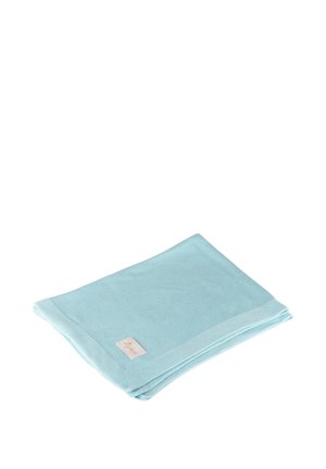Coperta piegata in tessuto lavorato a maglia azzurro chiaro con una piccola etichetta beige su sfondo bianco.