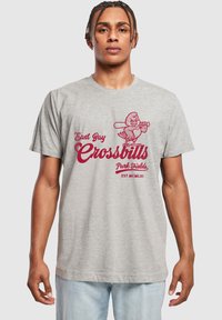 Lys grå bomull t-skjorte med et rødt grafisk design av en tegneserie-fugl som holder en kølle og teksten "East Bay Crossbills Park Fields EST. MCMLXI."