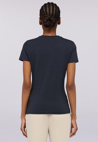 Námořnická modrá přiléhavá tričko s krátkými rukávy, kulatým výstřihem a hladkou texturou. Jednoduchý design bez viditelných vzorů nebo akcentů.
