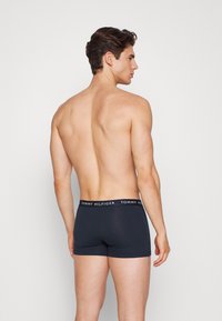 Caleçons boxers bleu marine à design uni avec une ceinture noire contrastante affichant "TOMMY HILFIGER" en blanc. Fabriqués en coton doux.