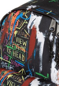 Mochila de lona con un fondo negro. Presenta patrones de graffiti abstracto coloridos en naranja, verde, azul y rojo, además de acentos de hardware metálico.