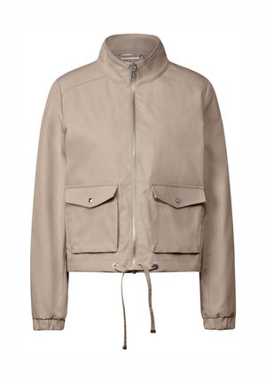 Veste cropped beige avec col montant, fermeture éclair sur le devant, deux poches poitrine et un cordon de serrage réglable en bas. Texture lisse.