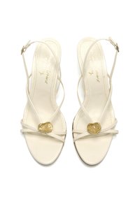 Tacones slingback blancos con tiras finas y un acento de hardware dorado en la parte delantera. Textura de cuero suave con un diseño de punta cuadrada.