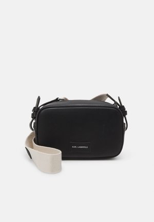 Black leather crossbody bag with a rectangular shape, featuring a fabric strap and a metal zipper. Label details on the front.