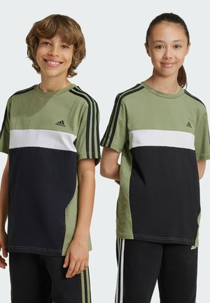 Camisetas color bloqueadas en verde, negro y blanco, con cuello redondo, mangas cortas y tres franjas negras en los hombros. Logotipo de Adidas en el pecho.