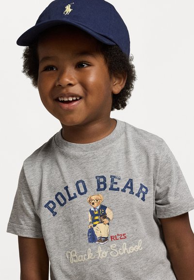 Grå bomull t-skjorte med en tegneserie-bjørn i et blått og gult antrekk med teksten "Polo Bear Back to School" og en marineblå caps.