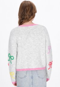 Pulover gri pufos, cu broderie colorată sub formă de fundiță în verde, roz și galben, având un guler și o margine roz cu model în dungi.