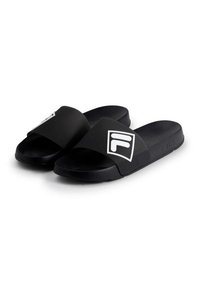 Black slide sandals with a wide strap featuring a white logo and branded accents, made from smooth rubber material for comfort.